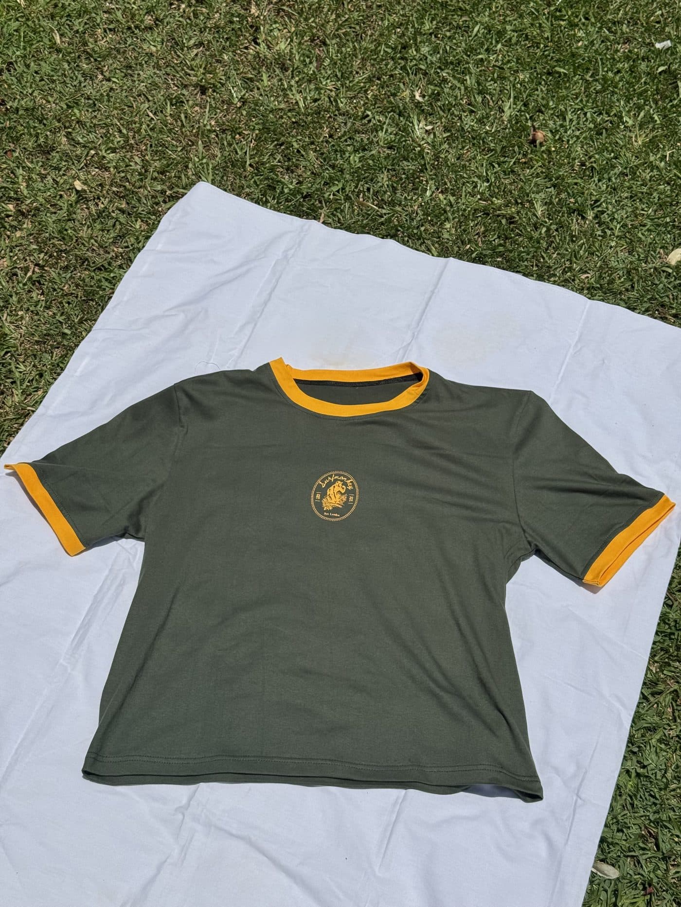 Jungle Crest Tee laid out on white cotton in the sun